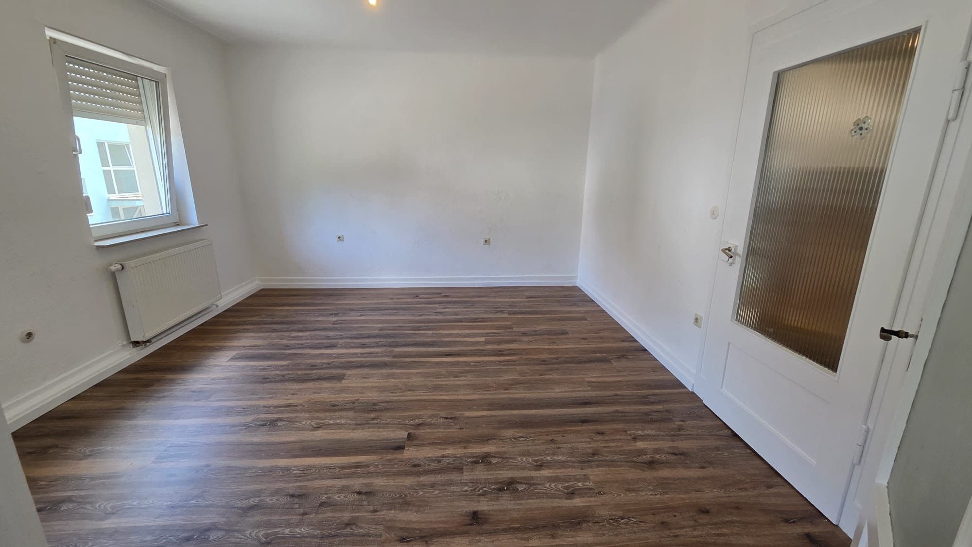 Renoviertes Zimmer mit weißen Wänden und neuem Laminat