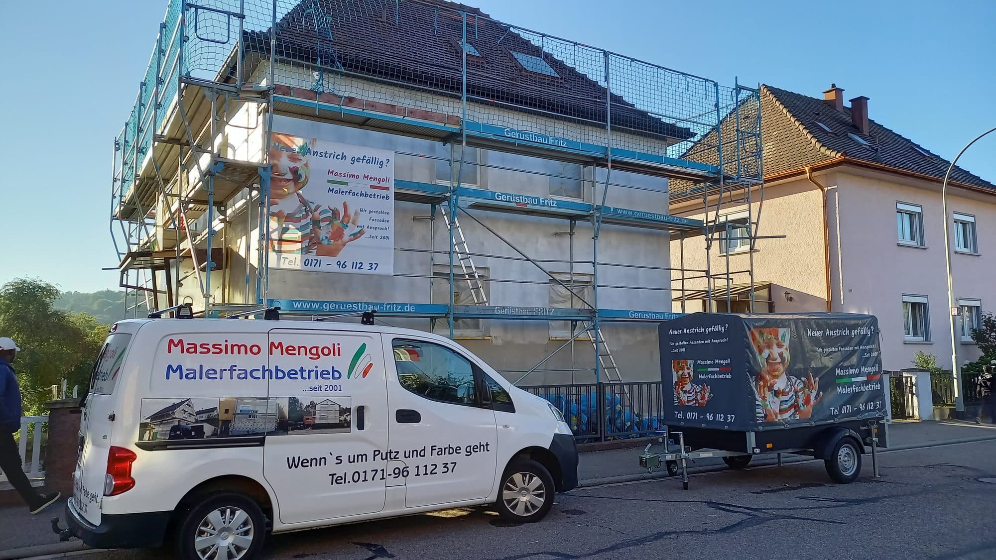 Firmenfahrzeug von Mengoli Malerfachbetrieb vor einer Baustelle mit Gerüst